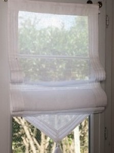 Rideau store en voile de lin entouré de drap de lin plissé blanc terminé par un pompon